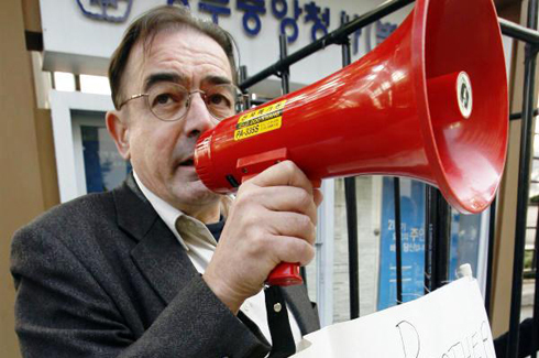 Rev. Tim Peters speaks through a egaphone at a protest in Seoul